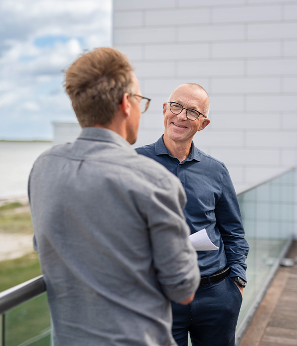 To mænd smiler og taler om sygefravær